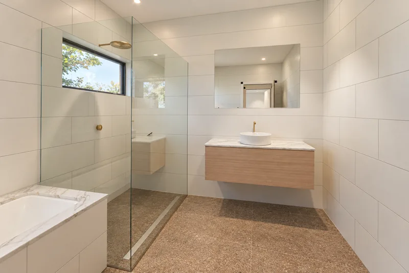 Main bathroom with a bath, vanity and high window