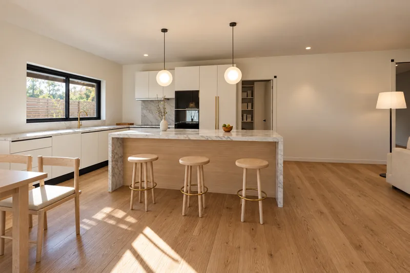 The kitchen island with three stools and the pendants above