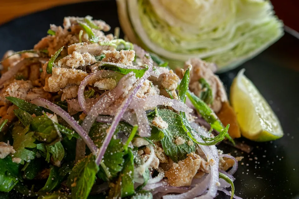 Larb with mint, red onion and toasted rice powder, a cabbage wedge and lime alongside