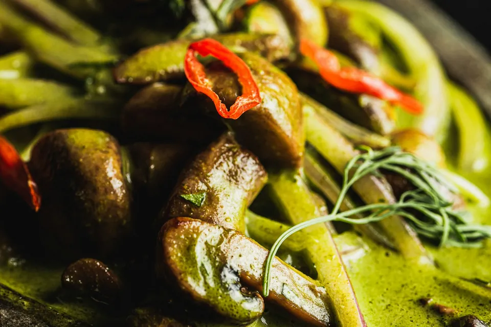 Close-up of green curry with mushrooms and red chilli