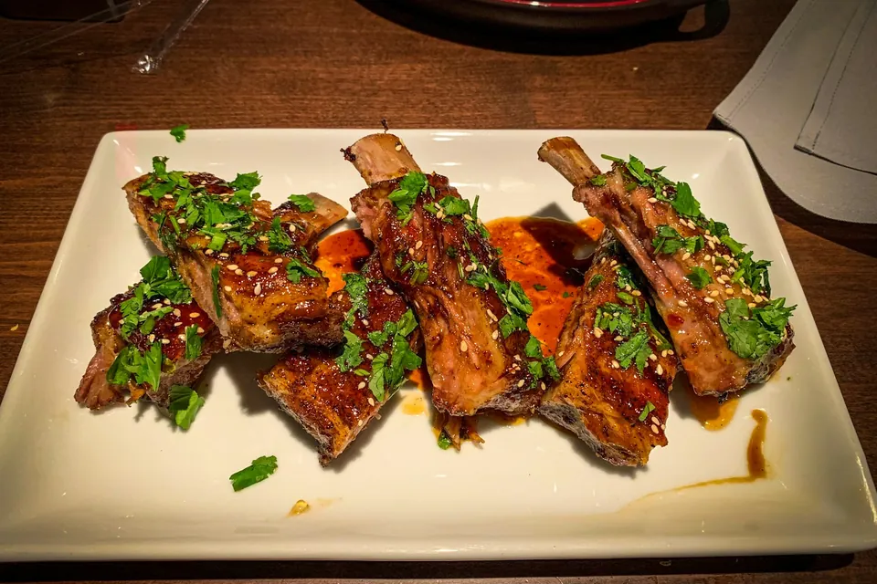 Glazed ribs scattered with coriander and sesame on a white plate