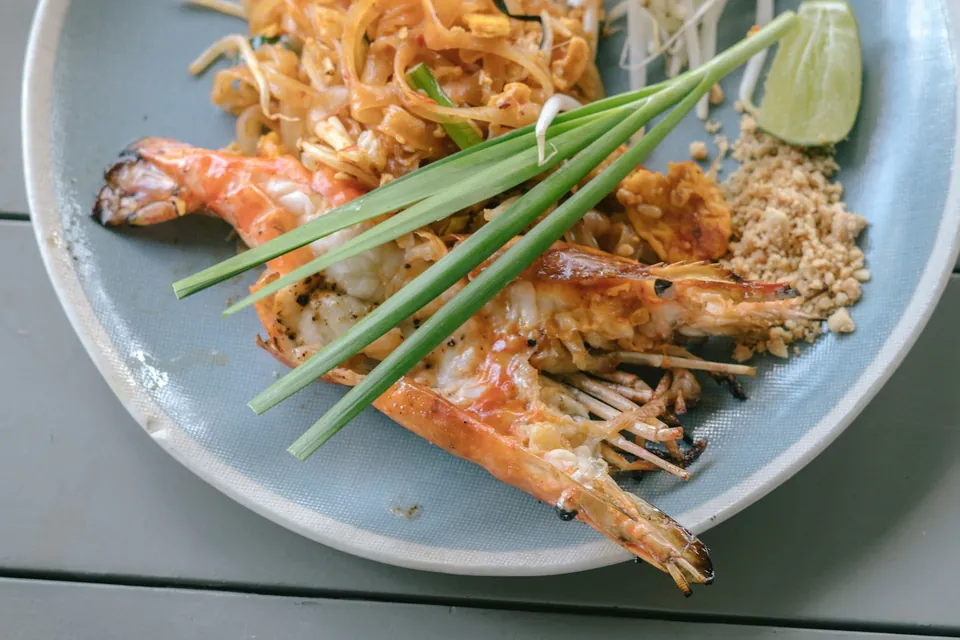 Pad thai with a whole grilled prawn, garlic chives, crushed peanut and lime