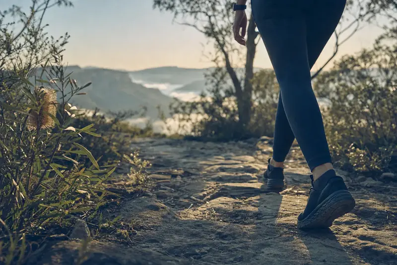 Walking shoes mid-stride on a sandstone bush track in morning light